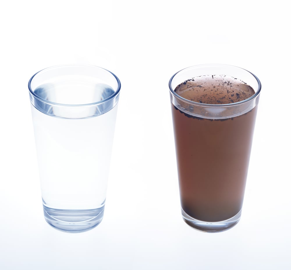 Two clear glasses are placed side by side, one filled with clear water and the other with murky, brown water with visible sediment.